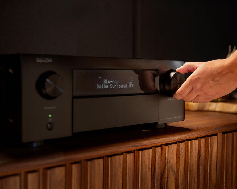 A man turning up the volume on an AVR